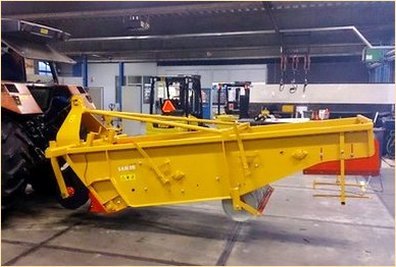 Una cosechadora, de SAMON ELLENS montada en la parte de atras de un tractor.